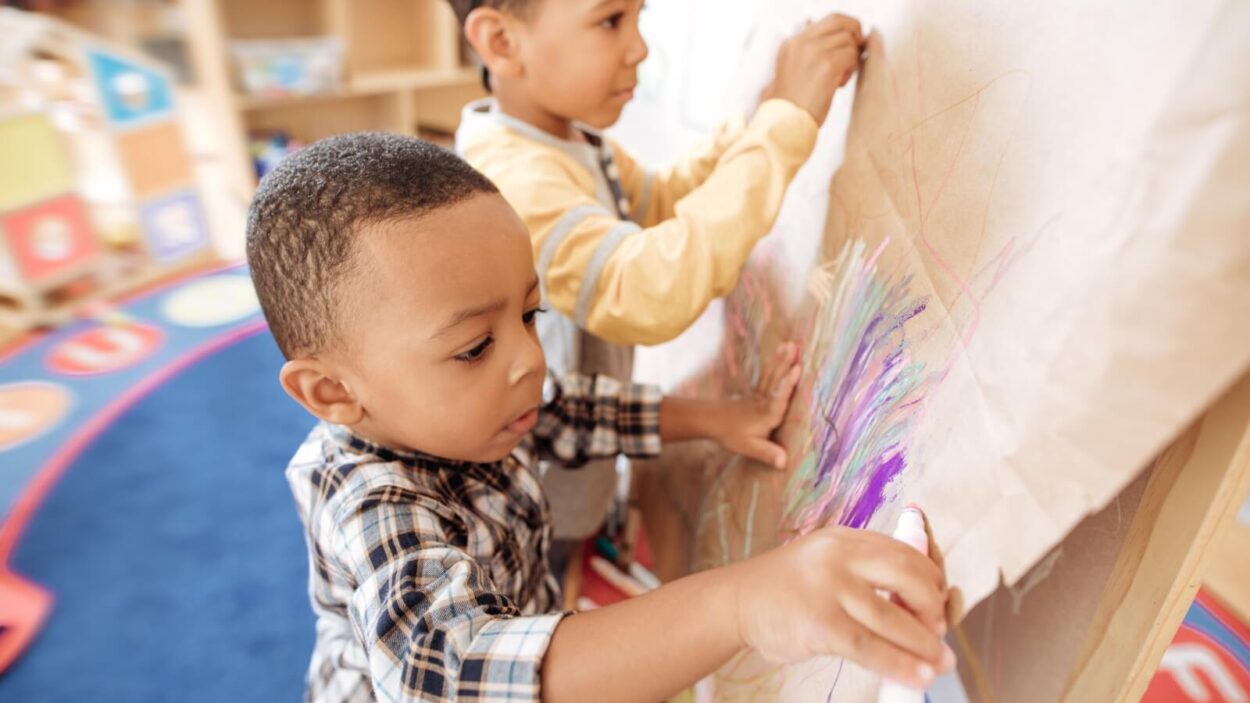 Two children using markers to color at daycare