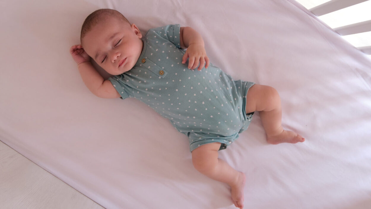 A baby laying on their back in a crib