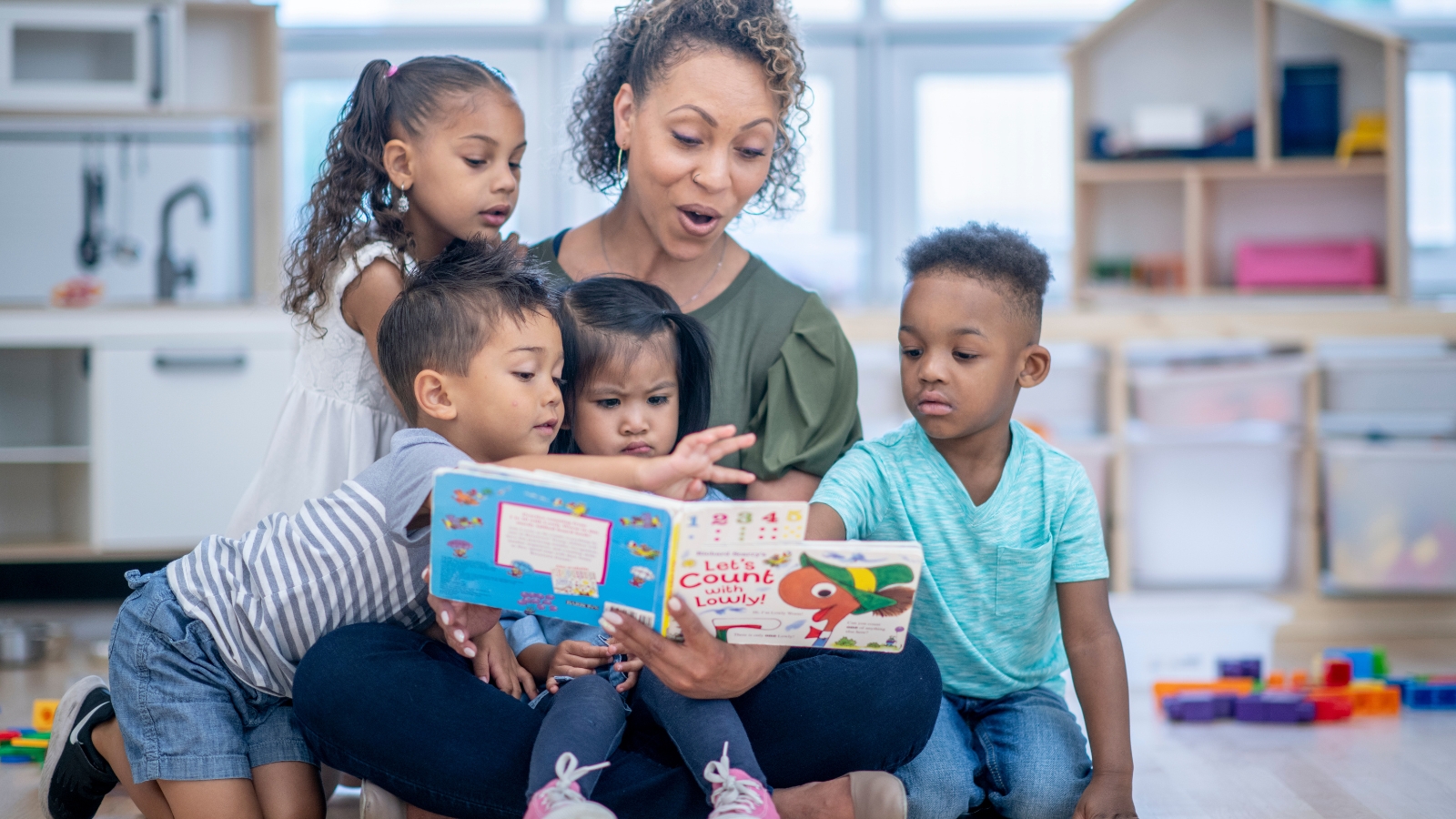 Woman reading a book to children in a classroom
