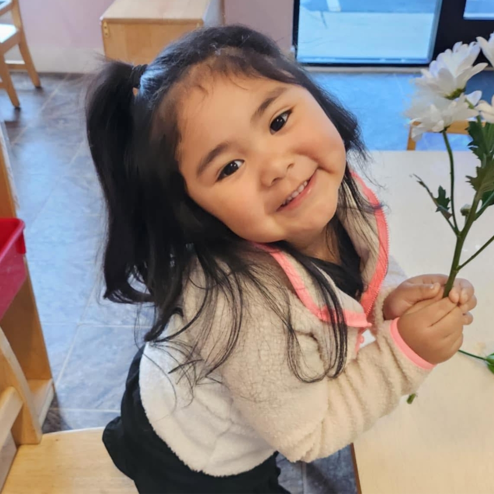 Girl holding a flower and smiling