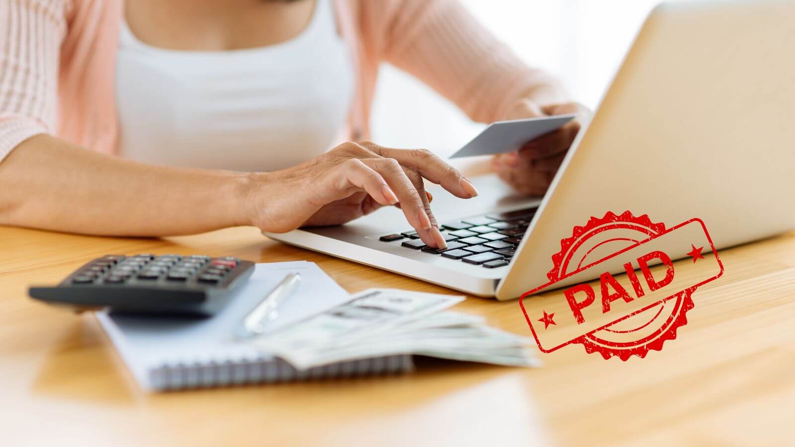 Woman paying online with credit card beside red paid stamp overlay